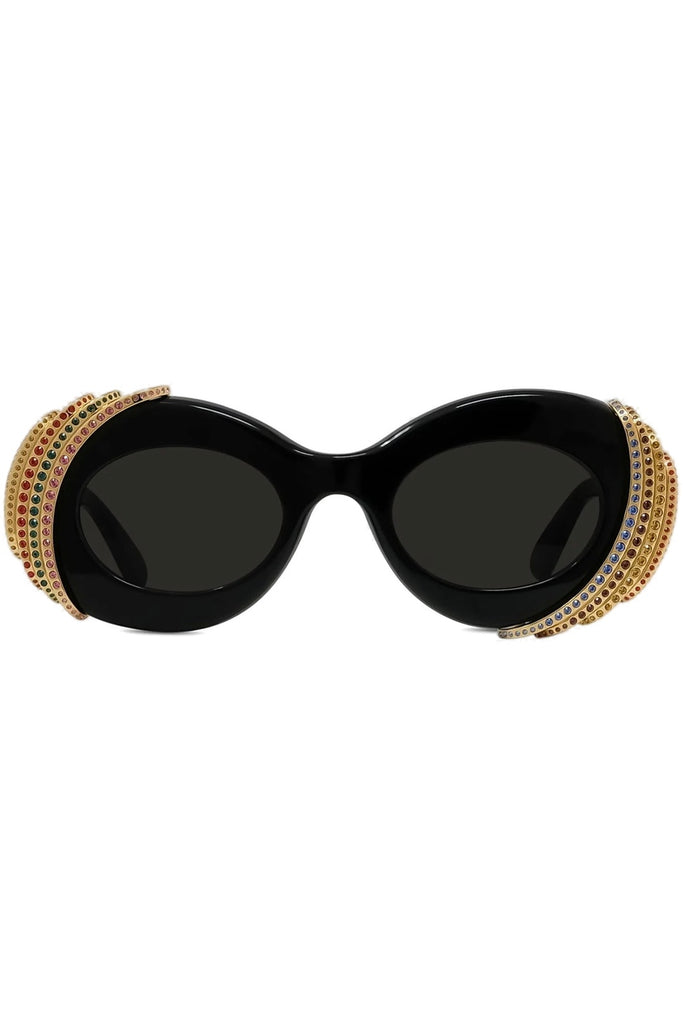 Oval sunglasses with a glossy black frame, dark lenses, and rows of gold rhinestones on the outer edges, shown against a plain white background.