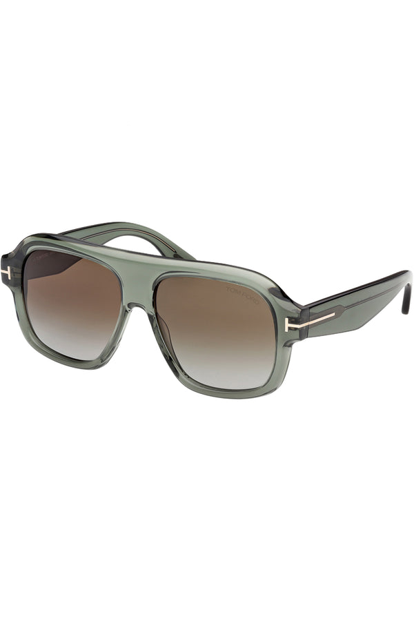 Rotated view of Tom Ford mask sunglasses in brown with translucent green frame and metal T details, shown against a plaid white background
