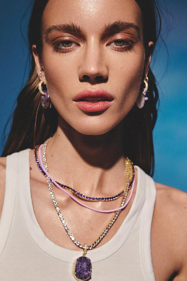 Model wearing the Amethyst pendant with pave connector in gold and purple colours from the brand CRYSTAL HAZE
