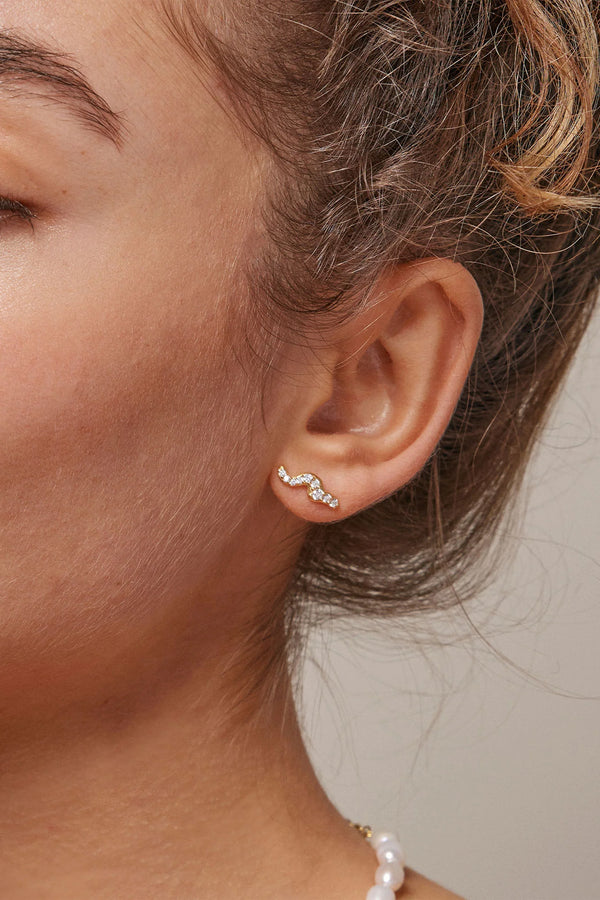 Model wearing the Lydia stud single earring in gold and clear colour from the brand ENAMEL COPENHAGEN