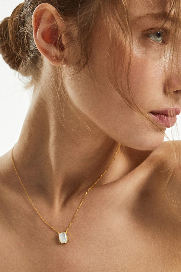 Model wearing the Palms necklace in gold and pearl colours from the brand MESH