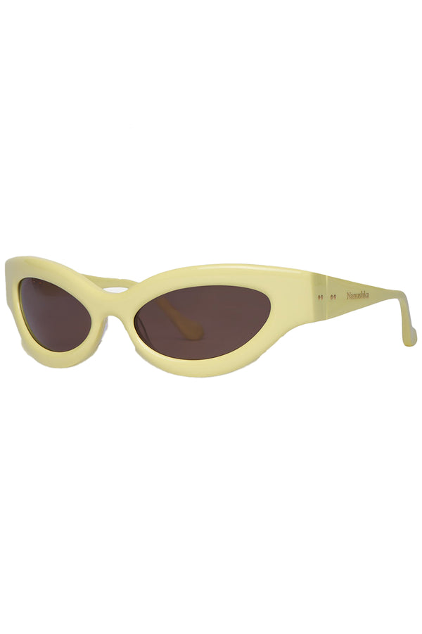 Rotated view of Nanushka oval sunglasses in pale yelllow, shown against a plaid white background.