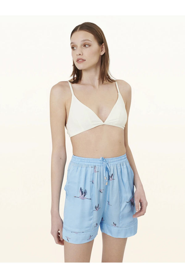 Model wearing the Sara heron-print elastic-waist shorts in light blue color from the brand PELSO